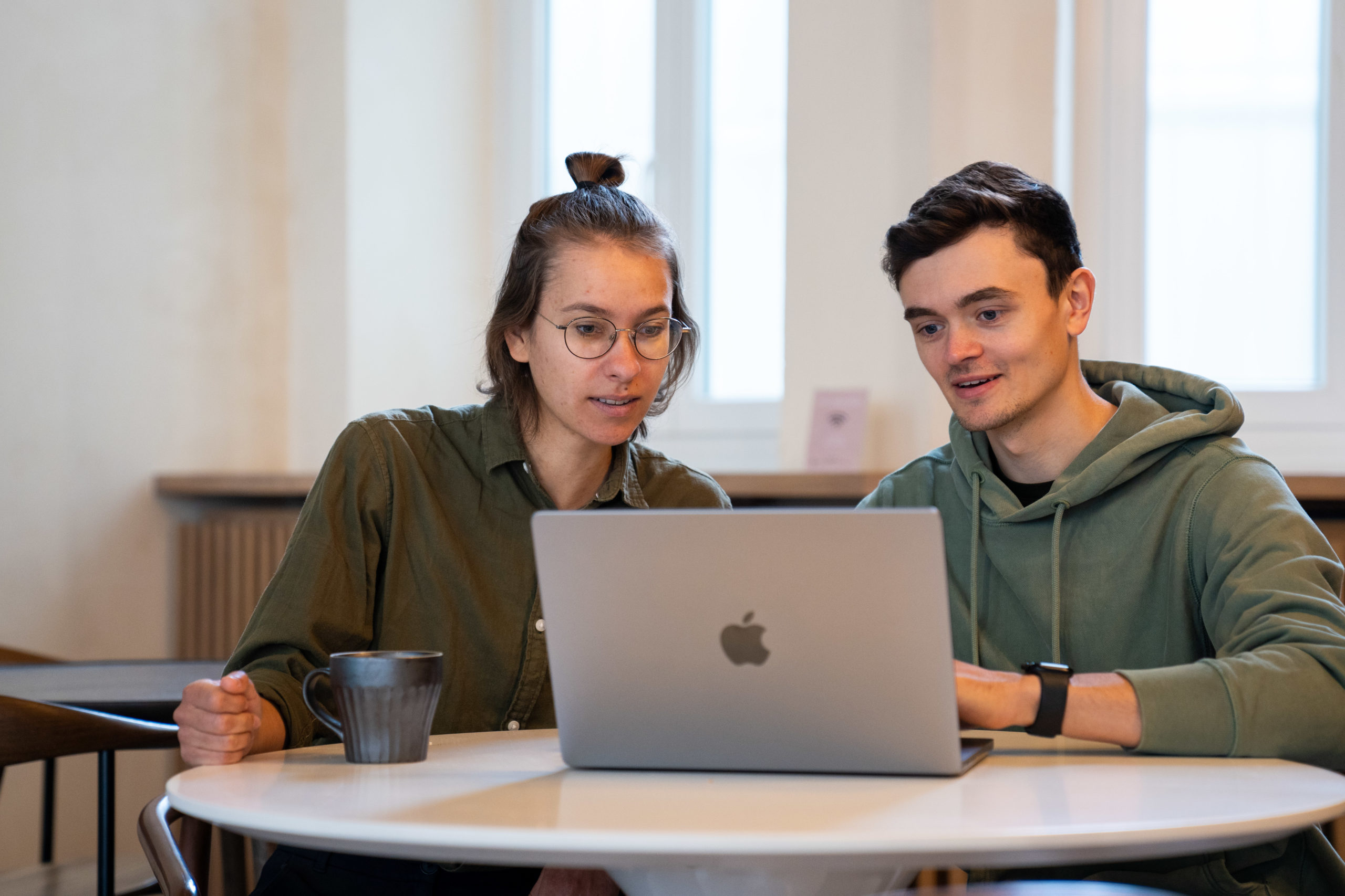 Zwei Personen sitzen vor einem Laptop und besprechen die Umsetzung einer professionellen YouTube Videoübersetzung im Unternehmen.